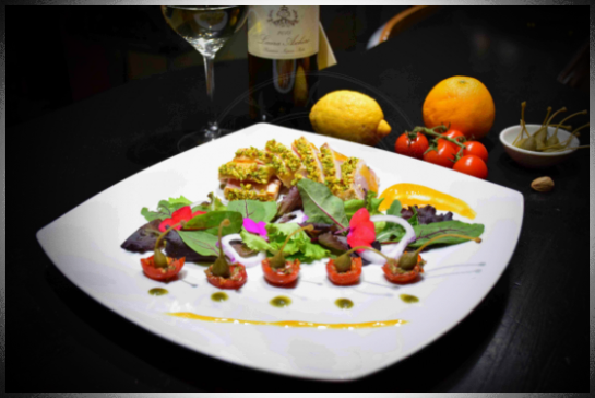Tagliata di pesce spada agli agrumi in crosta di pistacchi con pomodorini confit